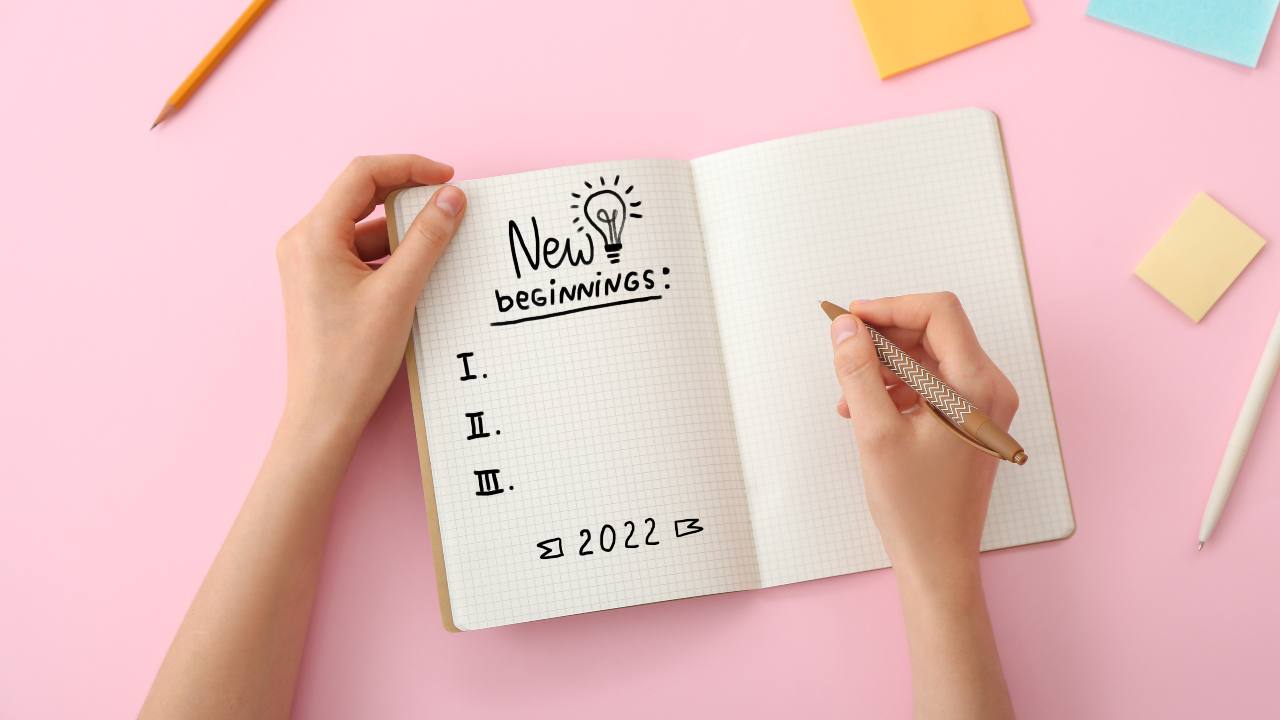 Young woman with notebook making to do list for 2022 year