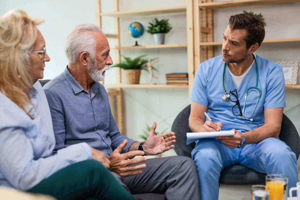 Un medico interagisce con una coppia di anziani, fornendo assistenza e supporto in un contesto domiciliare