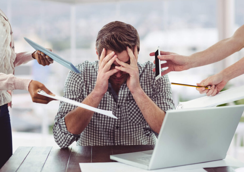 Un uomo seduto a una scrivania con le mani sulla testa, visibilmente stressato o pensieroso