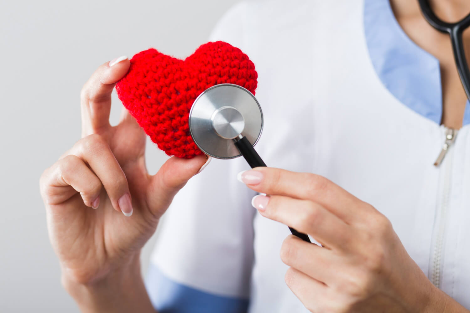 Un medico tiene in mano un cuore di stoffa, visitandolo metaforicamente con uno stetoscopio