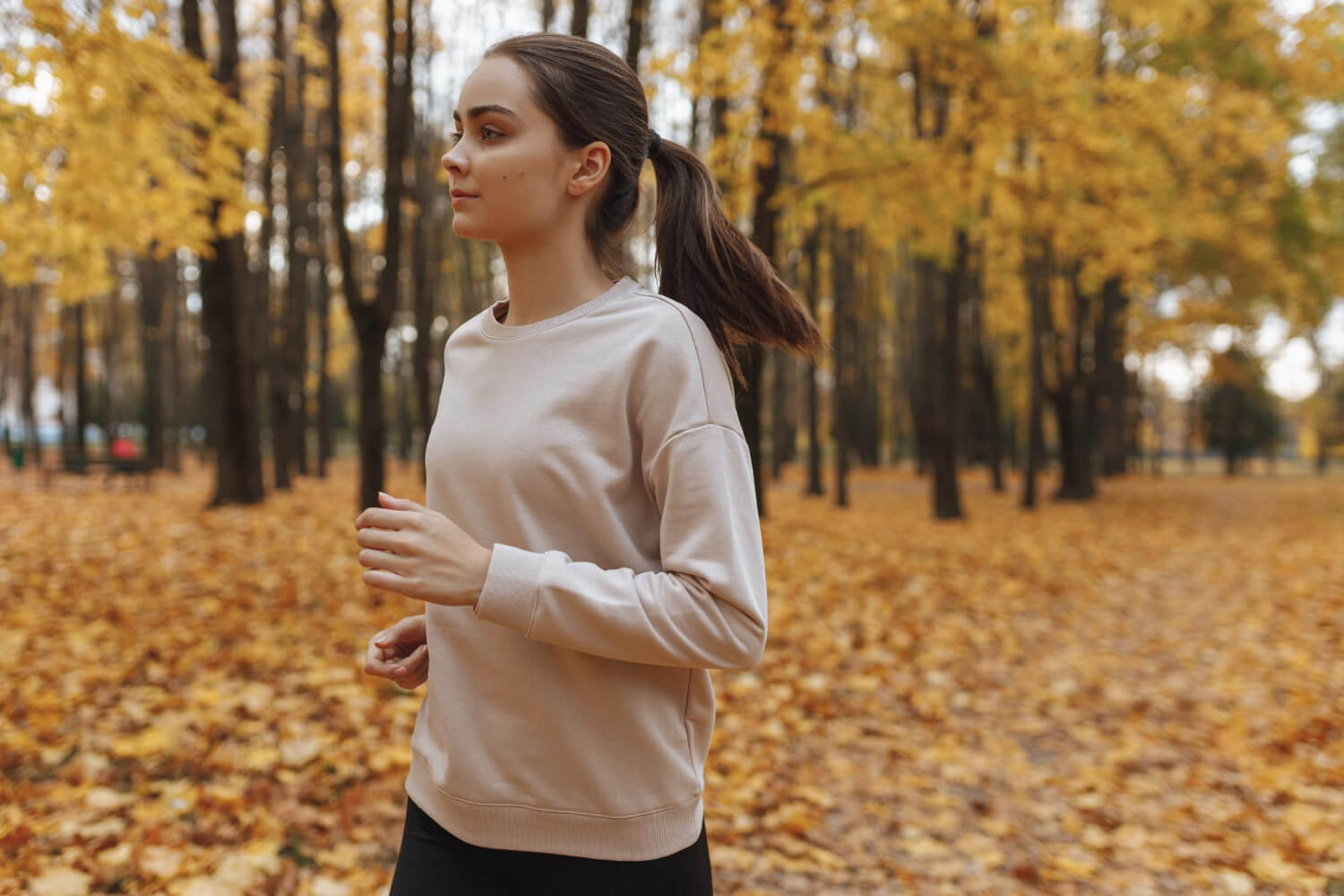 Donna che fa jogging in un parco autunnale per rafforzare il sistema immunitario con l'attività fisica all'aria aperta.
